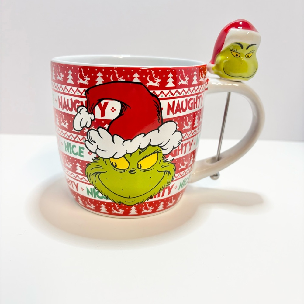 Red and white Grinch Christmas mug with a Grinch stirrer.